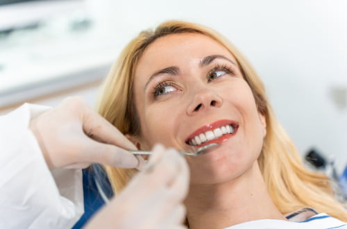 Female dentist examining a patient’s teeth during a smile makeover consultation in a dental clinic