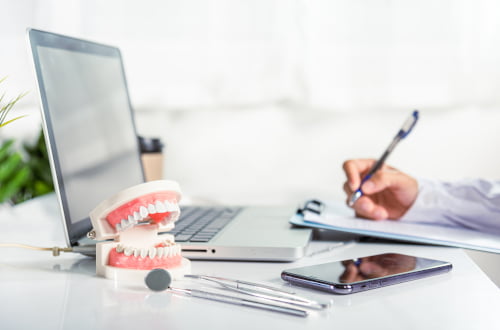 Dentist completing patient documentation and reviewing dental insurance information for CDCP direct billing in a dental clinic in Vaughan