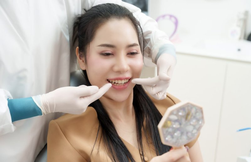 Female patient checking her smile after getting veneers at a Canadian dental clinic