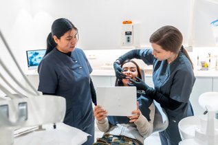 Dentist showing teeth whitening results to a smiling patient in Canada