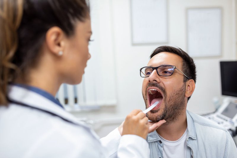 Male patient opening his mouth during dental examination to assess oral health problems such as dry mouth and cavities