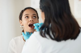 Woman at a dental clinic discussing dry mouth symptoms with a dentist during an oral health consultation