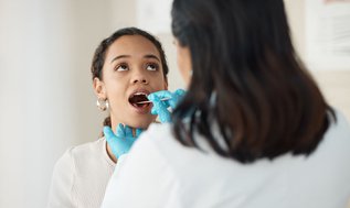 Woman at a dental clinic discussing dry mouth symptoms with a dentist during an oral health consultation