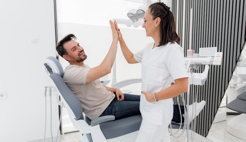 Patient and dentist high-fiving after a successful cosmetic dental procedure
