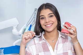 Invisalign clear aligners shown on a dental model beside traditional metal braces