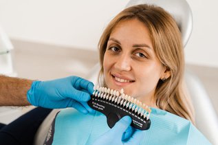Dentist comparing porcelain veneer shade with patient’s natural teeth