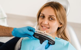 Dentist comparing porcelain veneer shade with patient’s natural teeth